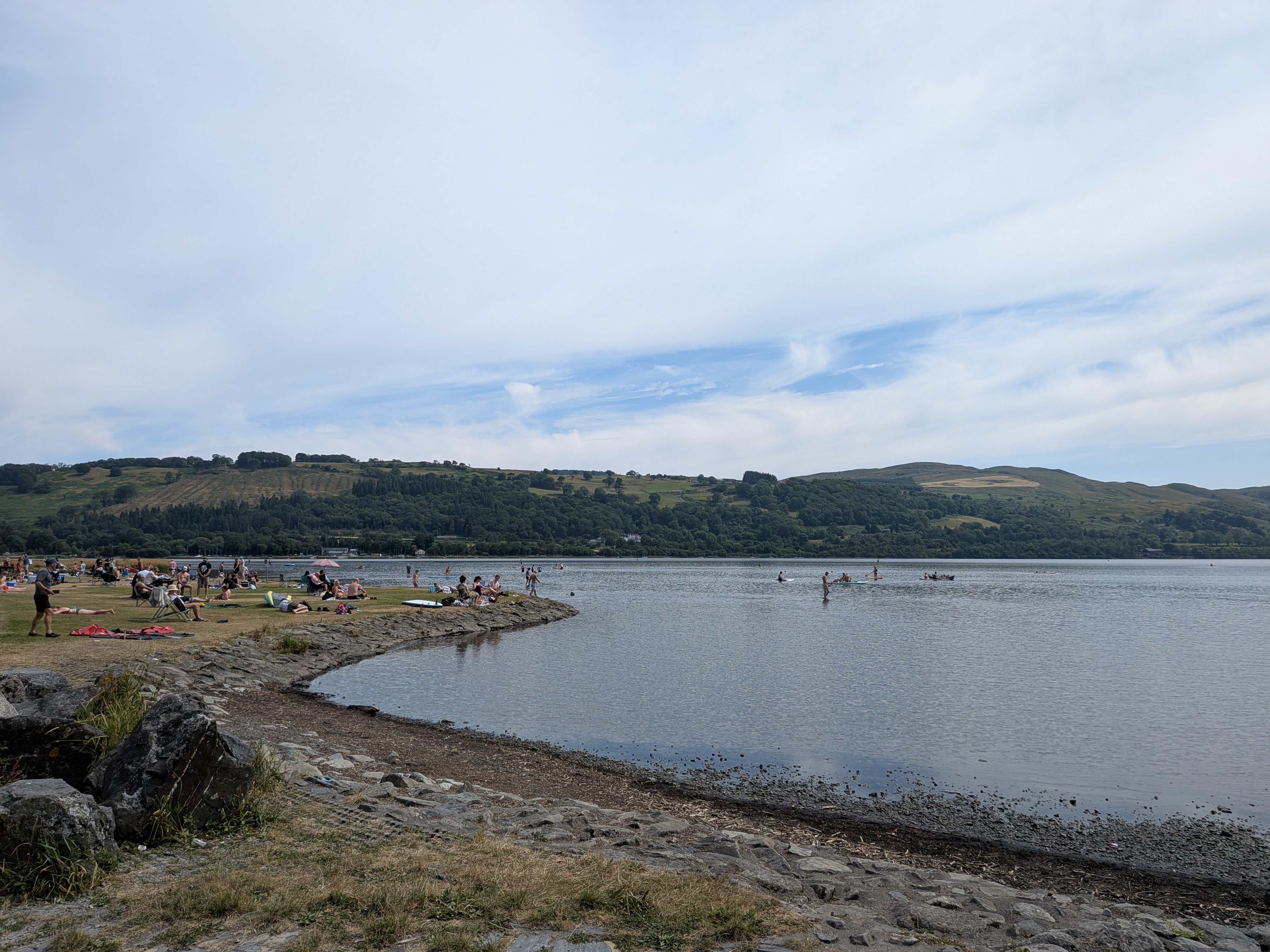 Llyn Tegid lake with people on the shore and hills behind
